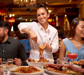 Food server dishing out pasta at table